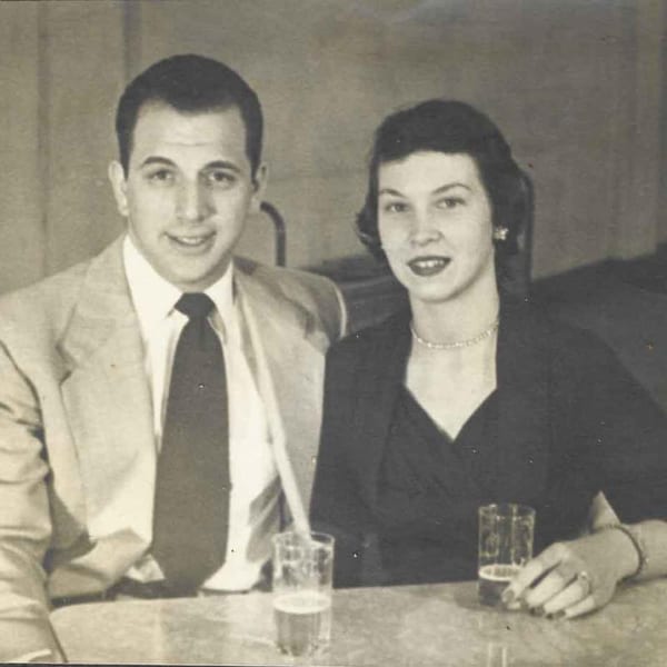 Vintage black and white photo of a smiling man and woman seated at a table with drinks.