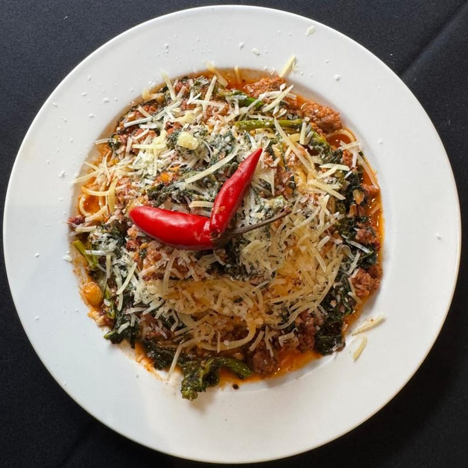 Marrelli's Italian Restaurant's spaghetti with meat sauce, greens, parmesan, and two red chili peppers.