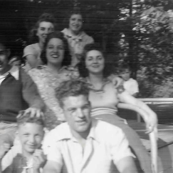 Black and white photo of a large family gathering, with adults and children smiling at the camera.