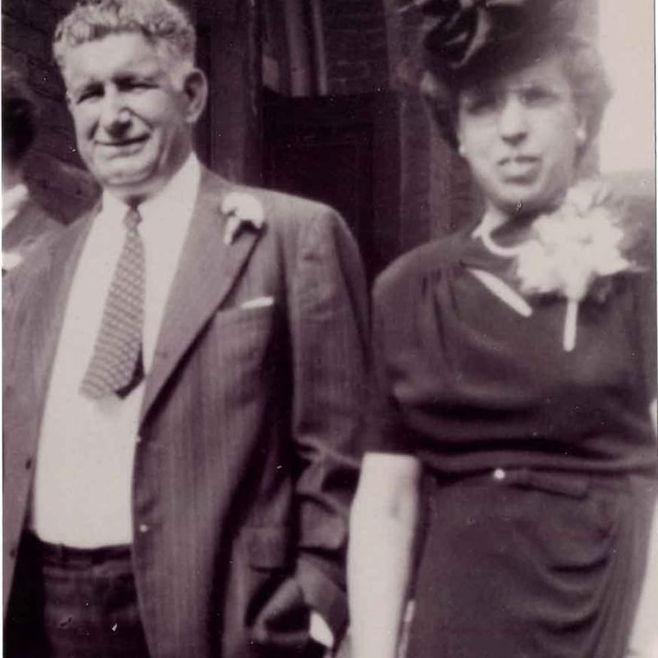 Black and white photo of a smiling man in a suit and a woman in a dress with a corsage.