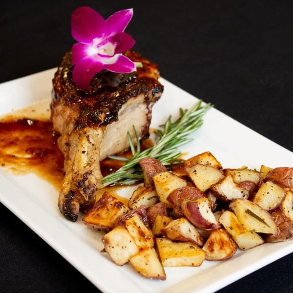 Marrelli's Italian Restaurant's pork chop with roasted potatoes, garnished with rosemary and an orchid.